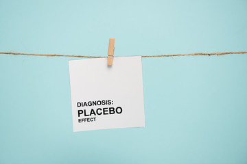 Card with diagnosis placebo effect lettering on rope with pin isolated on blue - obrazy, fototapety, plakaty