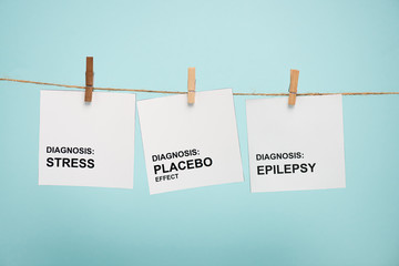 Cards with stress, placebo effect and epilepsy diagnoses lettering on rope with pins isolated on blue