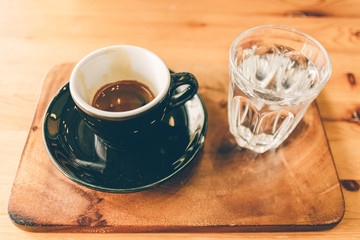 Set of espresso coffee cup with a glass of water on wooden table.