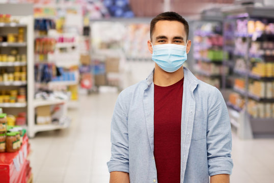 health, safety and pandemic concept - young man wearing protective medical mask for protection from virus over supermarket background