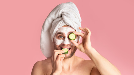 Millennial man makes face mask and eats cucumber