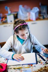 little girl at home performs homework in the kitchen on the table