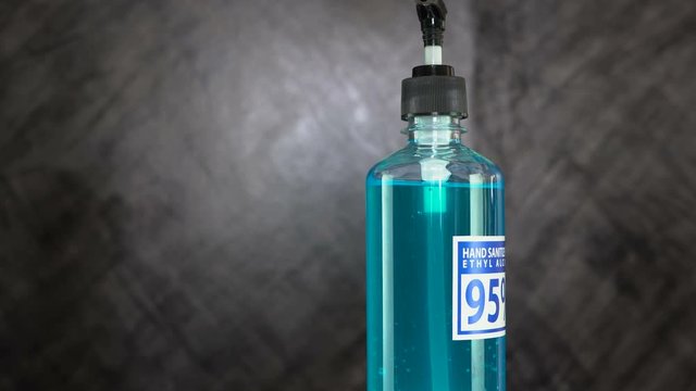 Bottle of hand sanitizer blue gel with ingredient ethyl alcohol 95% on dark background, concept prevent disease Covid-19, rotate and zoom out camera