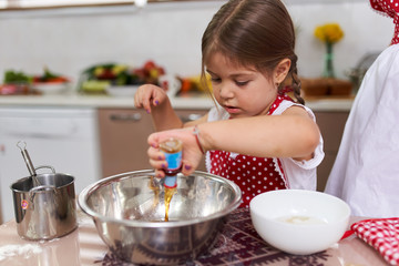 Little girl cooking with her mom