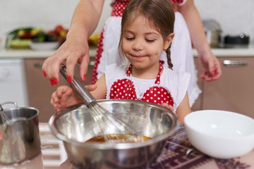 Little girl cooking with her mom
