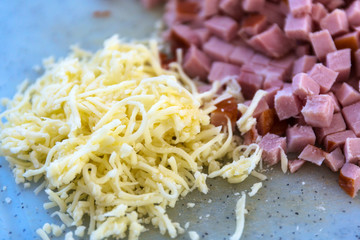 grated cheese and diced ham on a board for spaghetti carbonara