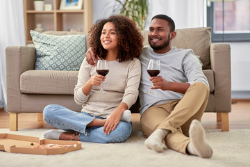 Fototapeta na wymiar leisure, people and valentines day concept - happy african american couple with wine and takeaway pizza at home