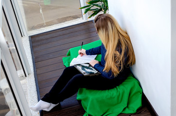 Teen girl reads an e-book on a tablet and does homework. Isolation from the outside world. World Quarantine, Coronovirus Pantemia, COVID-19. Distance learning. close-up. A teenager is sitting on the