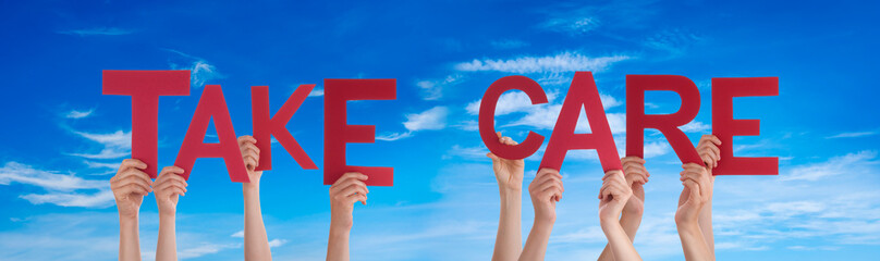 People Hands Holding Colorful English Word Take Care. Blue Sky As Background