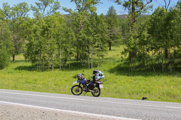 The motorcycle stands on the side of the road. Travel to the Altai Mountains. Stopping after a long trip.