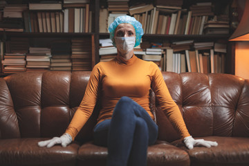 Woman with protective antiviral mask sitting at home in isolation / quarantine.