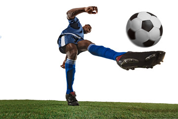 Football or soccer player on white background with grass. Young male sportive model training, practicing. Attacking, catching. Concept of sport, competition, winning, motion, overcoming. Wide angle.