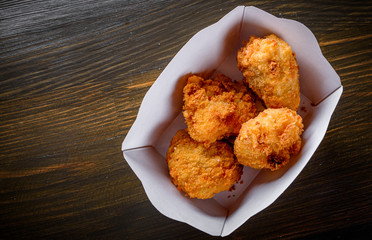 Fried breaded chicken in white cardboard box on wooden table background