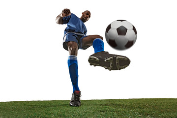 Football or soccer player on white background with grass. Young male sportive model training, practicing. Attacking, catching. Concept of sport, competition, winning, motion, overcoming. Wide angle.