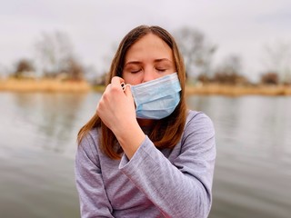 a teenage girl taking off a medical mask
