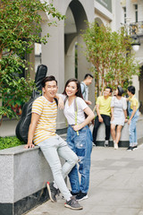 Fototapeta premium Cheerful Vietnamese college students standing at campus entrance and looking at camera