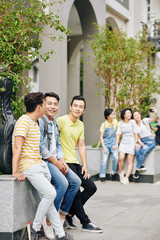 Fototapeta premium Cheerful students resting outdoors after classes in university and discussing homework and plans for the weekend