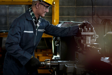 Industrial engineer worker wearing helmet and safe glasses  operating with machinery at manufacturing plant factory, working with machine in industry concept