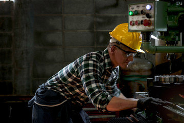 Fototapeta na wymiar Industrial engineer worker wearing helmet and safe glasses operating with machinery at manufacturing plant factory, working with machine in industry concept