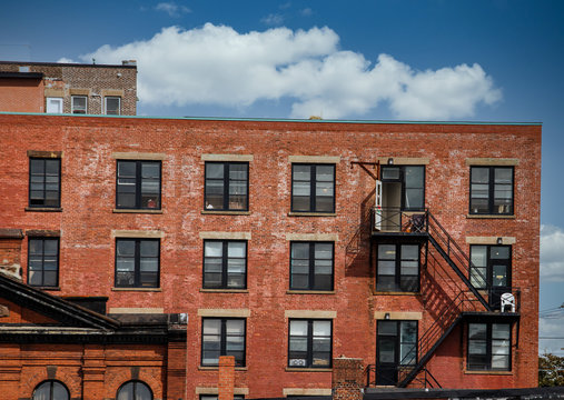 Black iron fire escapes on old brick buildings in Canada - Powered by Adobe
