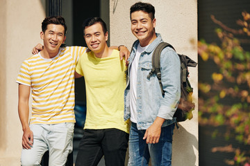 Group of cheerful Asian students hugging and smiling at camera