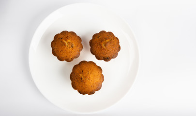 Sweet homemade cupcake with raisins on a white plate.
