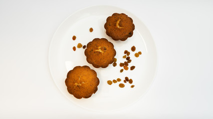 Sweet homemade cupcake with raisins on a white plate.