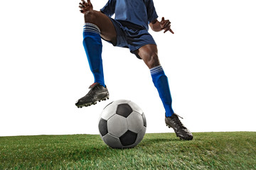 Football or soccer player on white background with grass. Young male sportive model training,...