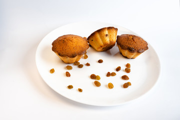 Sweet homemade cupcake with raisins on a white plate.