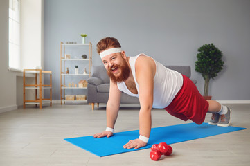 Funny fat man doing exercises on the floor smiling on the floor at home.