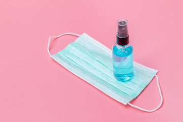 A small bottle of spraying alcohol or gel for hand hygiene and medical mask corona virus protection. - Health care concept.