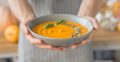 Man holding fresh hot pumpkin carrot soup