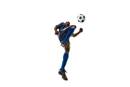 Football or soccer player on white background with grass. Young male sportive model training, practicing. Attacking, catching. Concept of sport, competition, winning, motion, overcoming. Wide angle.
