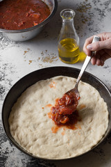 Pizza in the making. Red tomato sauce, yellow olive oil. White and black background