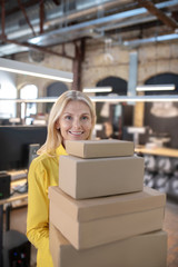 Blonde woman standing with pile of boxes