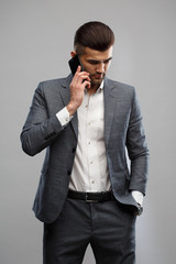 Young Asian man in a business suit talking on the phone Isolated on a gray background.
