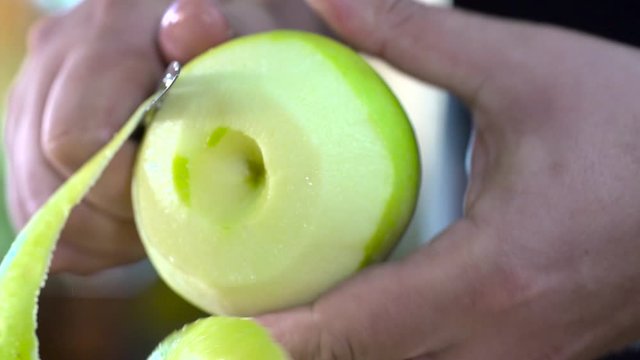 mains qui &eacute;pluche une pomme en cuisine