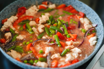 Thai Panang chicken Curry in a frying pan on the stove. Cooking. Boiling. Phanaeng Curry is a Thai dish with chicken, red curry sauce and vegetables. Thai cuisine. Thai food.