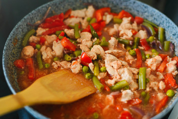 Thai Panang chicken Curry in a frying pan on the stove. Cooking. Boiling. Phanaeng Curry is a Thai dish with chicken, red curry sauce and vegetables. Thai cuisine. Thai food.