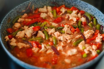 Thai Panang chicken Curry in a frying pan on the stove. Cooking. Boiling. Phanaeng Curry is a Thai dish with chicken, red curry sauce and vegetables. Thai cuisine. Thai food.