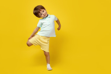 Fototapeta na wymiar Funny kid listening music and dance over yellow background.