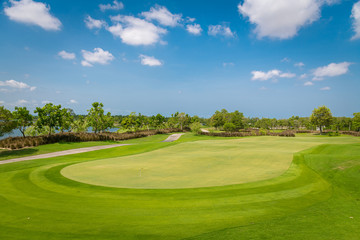 Obraz premium A beautiful view green golf course big tree ,sand bunker and blue cloud sky background.