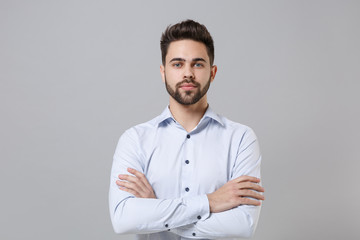 Handsome confident young unshaven business man in light shirt posing isolated on grey background...