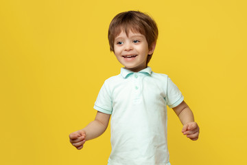 Adorable little kid in casual summer outfit with bright smile posing over yellow background.