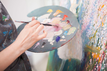 Cropped close up of a female artist mixing oil paint on a palette