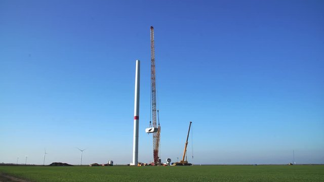 Building process of wind energy power tower mill, under construction. Time-lapse. Assembling rotor, tower, column, pillar. Green, clean, renewable energy. 