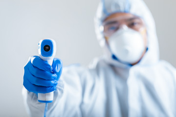 Asian man directs infrared thermometer on camera