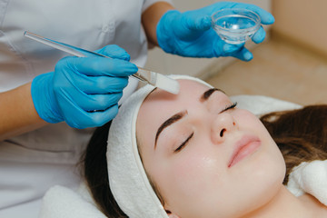 Beauty salon, cosmetician aplying facial peeling mask. Skin treatment concept.
