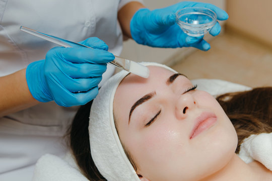 Beauty salon, cosmetician aplying facial peeling mask. Skin treatment concept.