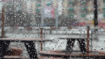 Close-up of drops of rain flow down the window glass. View of blurred silhouettes of city life through wet glass. Melting snow, drops of water flowing down the glass. Shooting in slow motion - Powered by Adobe